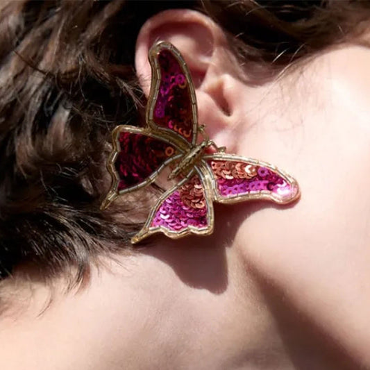 Close-up of Orek Noira Scarlet Flutter Earring earrings detail, a red sequin butterfly with delicate, fl