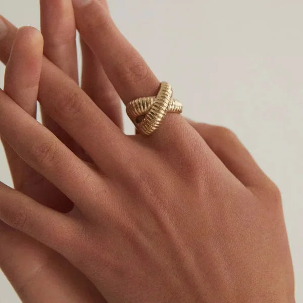 Close-up of Orek Conch Cross Ring ring detail, a shell-shaped curve crossed with a doub