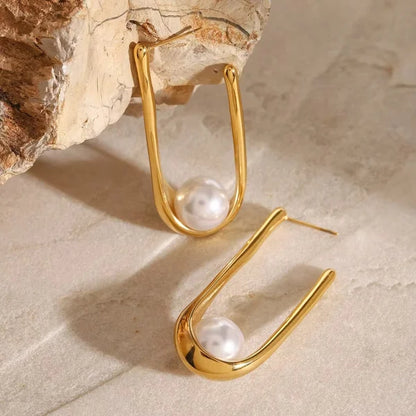 Close-up of Orek Era U Shell Pearl Earrings earrings detail, a sculpted U-shaped shell form finished 