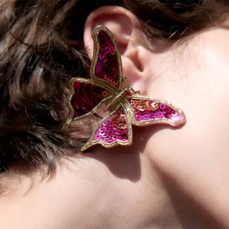 Close-up of Orek Noira Scarlet Flutter Earring earrings detail, a red sequin butterfly with delicate, fl