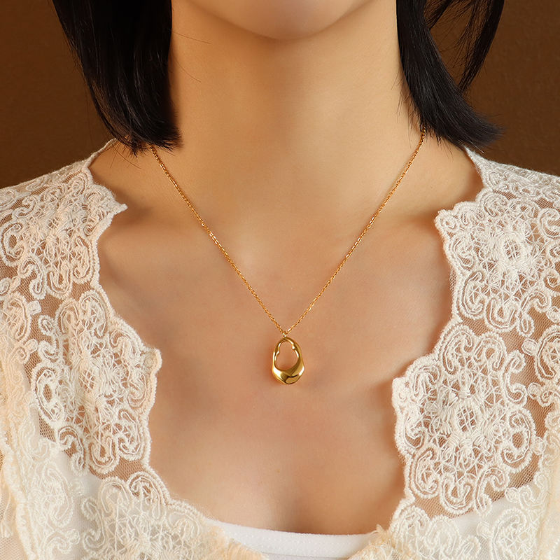 Orek Aurum Flow Pendant Necklace necklace on jewellery display, a smooth, sculptural pendant that curves