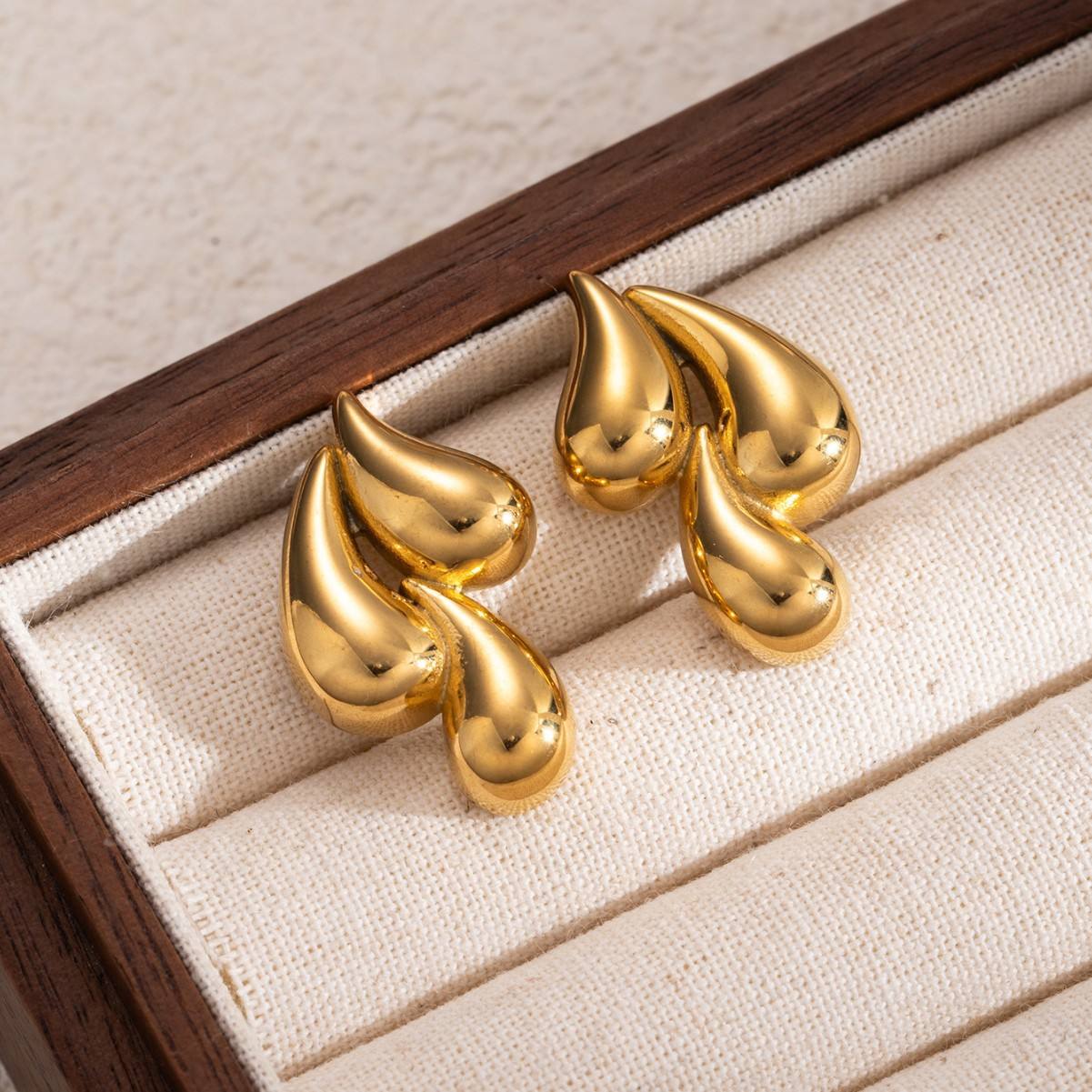 Orek Golden Swirl Drop Earrings earrings on jewellery display, a fluid, swirling drop that catches ligh