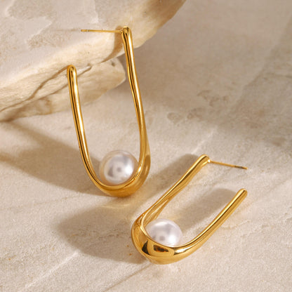 Orek Era U Shell Pearl Earrings earrings on jewellery display, a sculpted U-shaped shell form finished 
