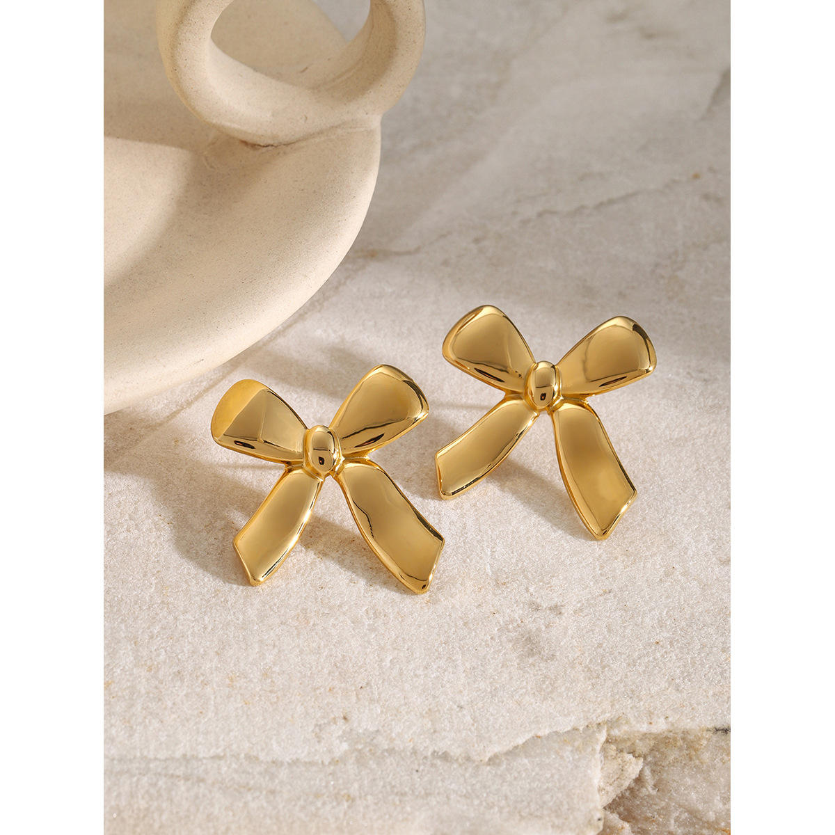 Close-up of Orek Charming Bow Stud earrings detail, a delicate, polished bow silhouette