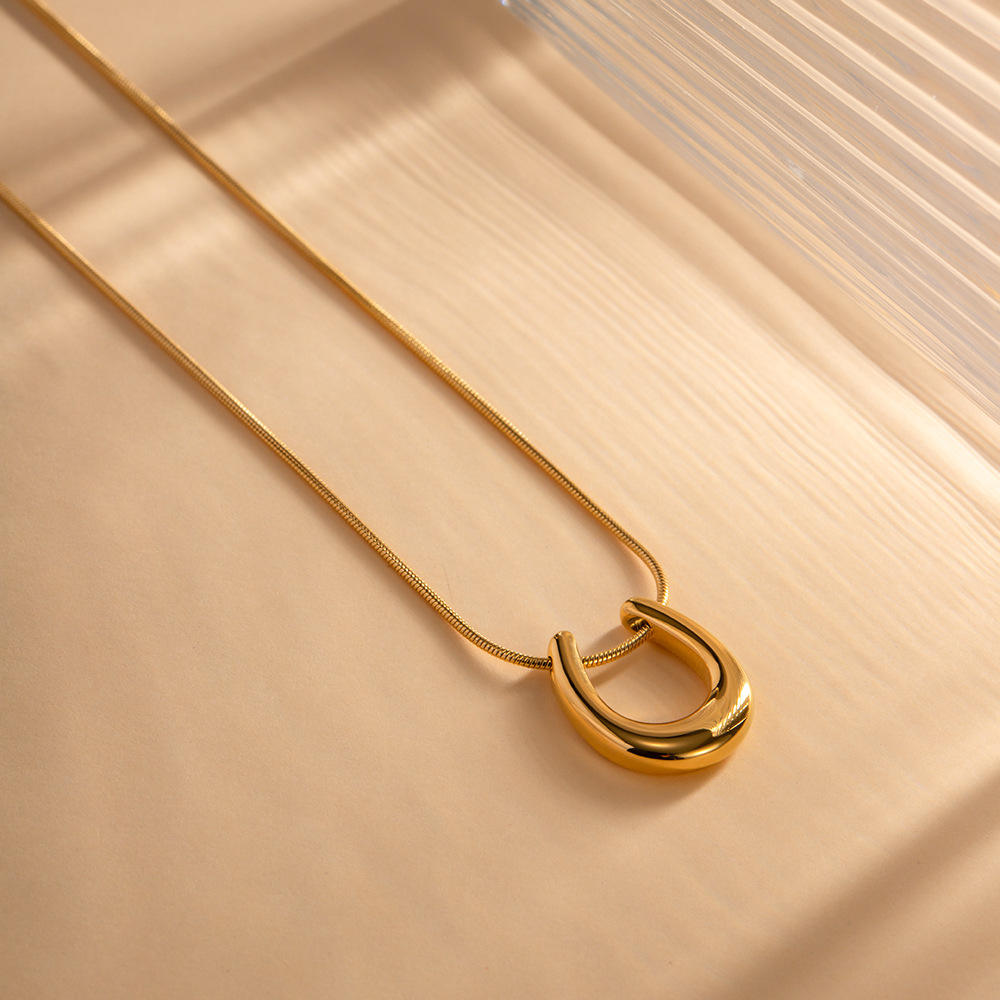 Orek Evara Lunar Sweep Necklace necklace on jewellery display, a minimalist crescent-moon curve pendant