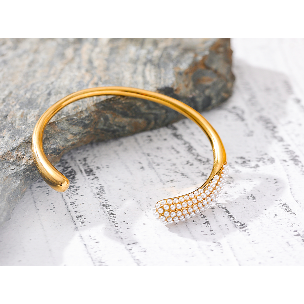 Orek Perla Pearl Inlaid Bangle bracelet on jewellery display, a row of inlaid pearls set flush into a 