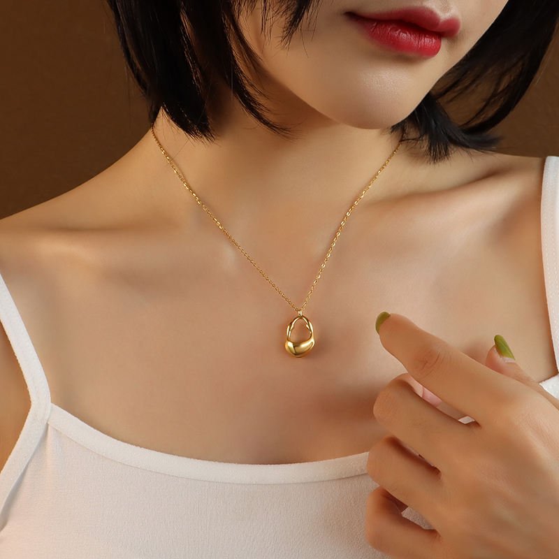 Close-up of Orek Aurum Flow Pendant Necklace necklace detail, a smooth, sculptural pendant that curves