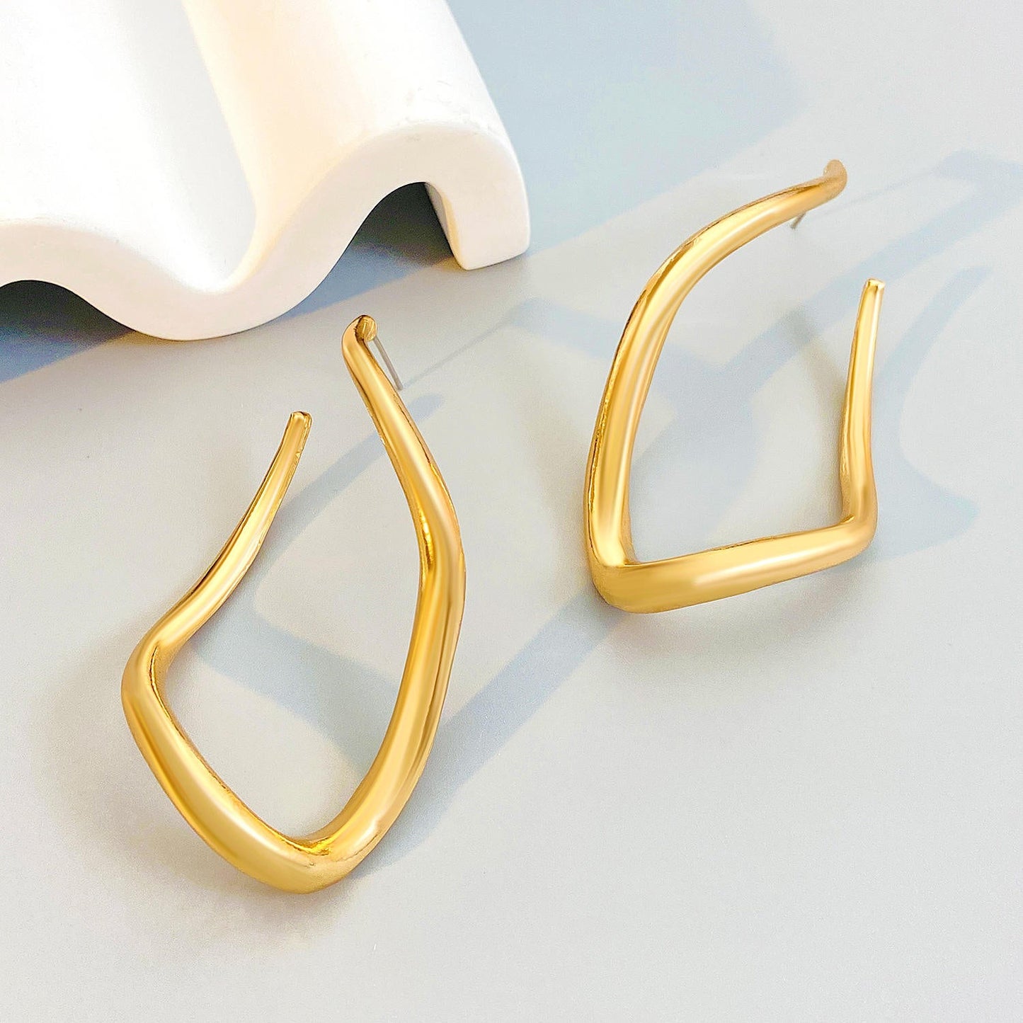 Orek Ciela Abstract Twist Dangler earrings on jewellery display, an abstract, twisted metal silhouette wi