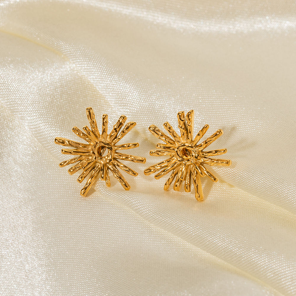 Close-up of Orek Evara Burning Sun Studs earrings detail, a textured, lava-finish sunburst with ra