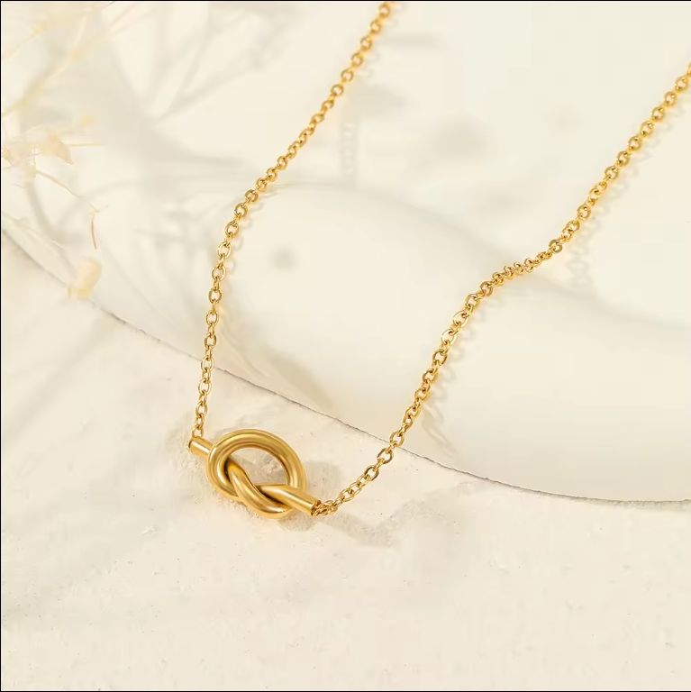 Close-up of Orek Heart Love Knot Necklace necklace detail, an interlocking heart and love-knot pend