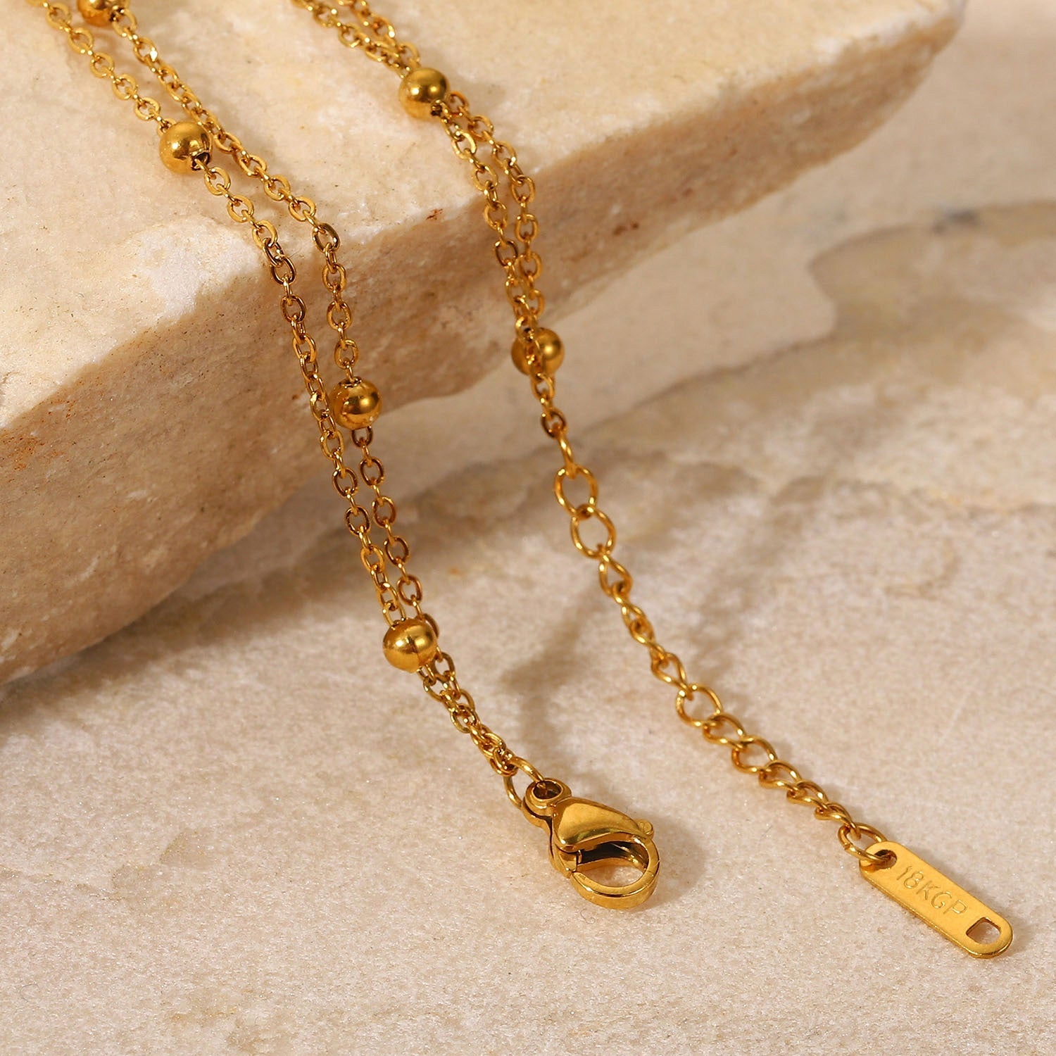 Orek Ira Double Chain Bracelet bracelet on jewellery display, two fine chains layered with a row of sm