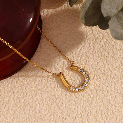 Close-up of Orek Evara Horseshoe Necklace necklace detail, an asymmetrical horseshoe pendant lined 