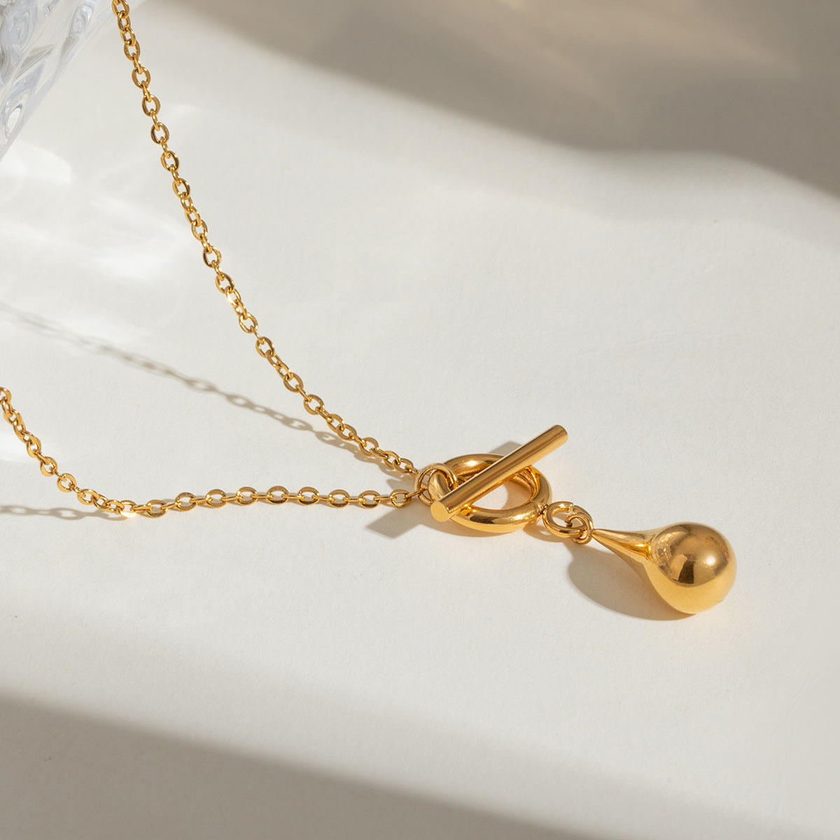 Flat lay image of the Orek Ciela Drop Knot Necklace displaying a minimal waterproof gold pendant necklace for everyday wear.