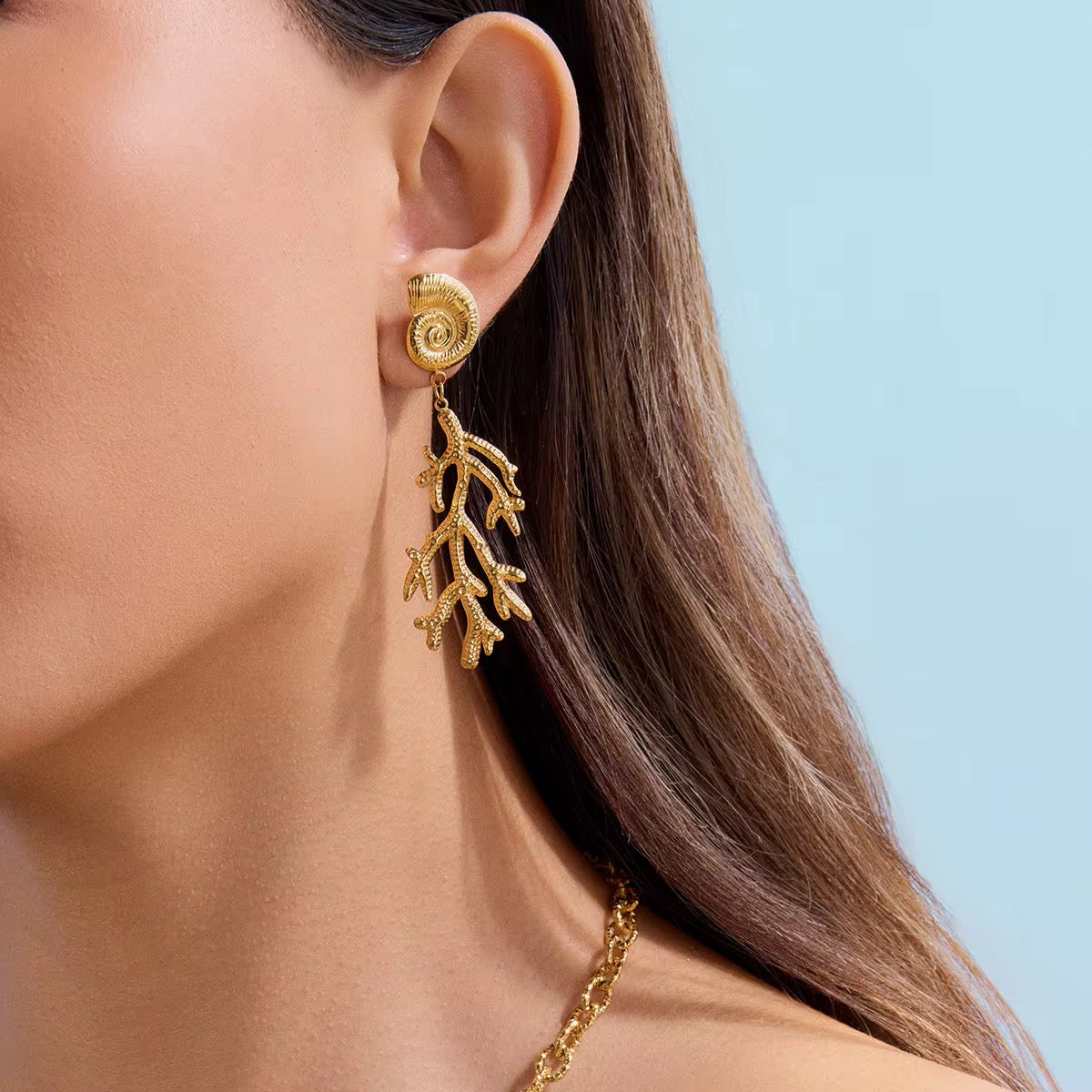 Woman wearing Orek Sora Coral Muse Dangler gold statement earrings